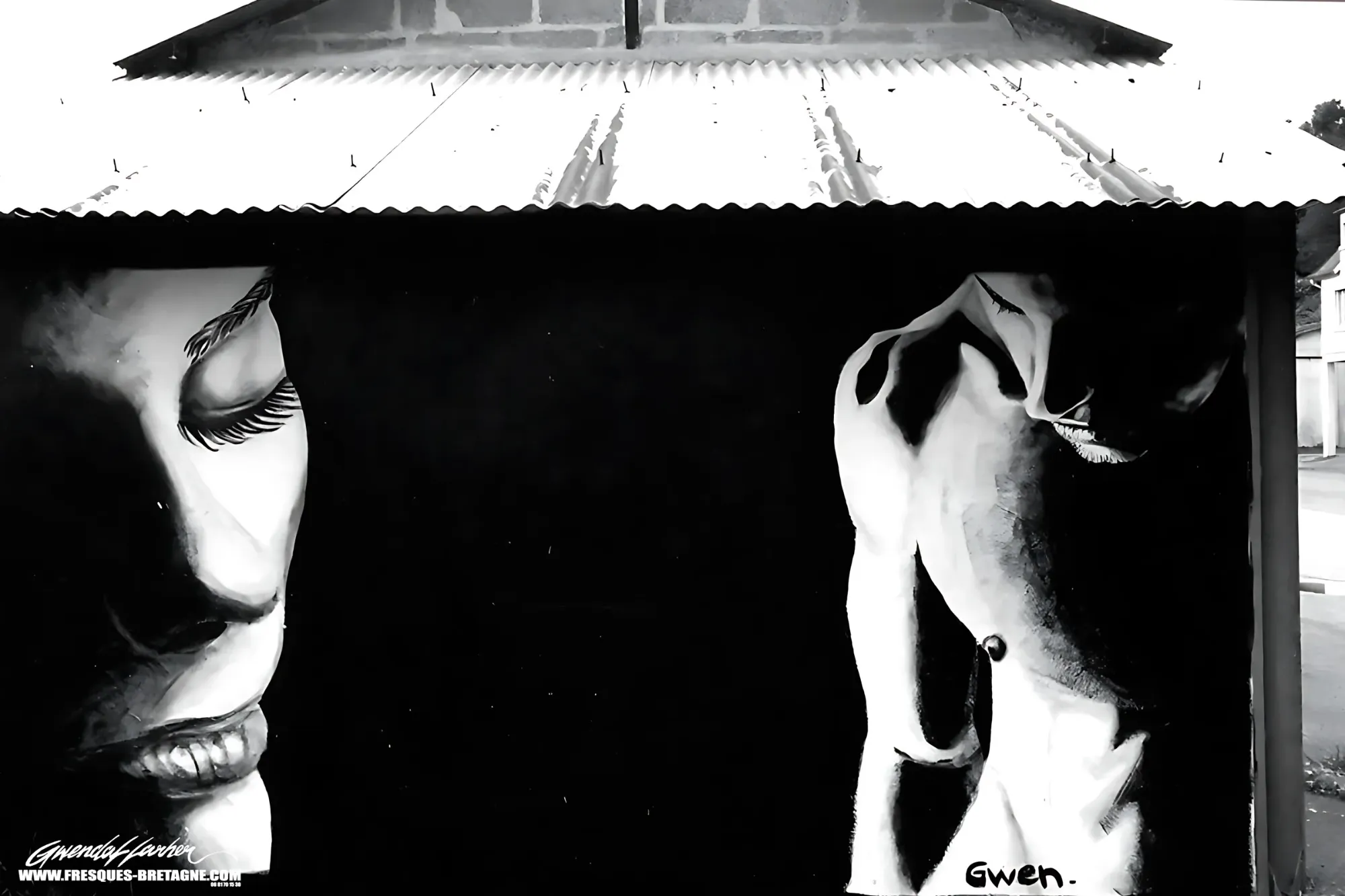 Portraits street art noir et blanc de deux visages de femmes peints sur la façade d'un hangar à toit de tôle, signature Gwen, fresque murale d'un artiste graffeur
